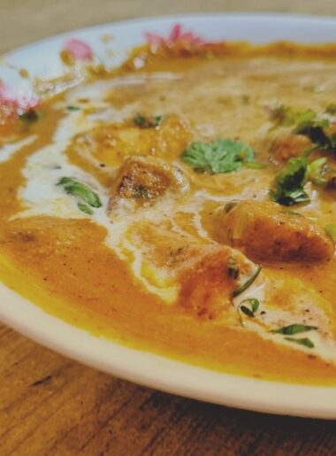 Plating of Paneer Butter masala with fresh cream on top.